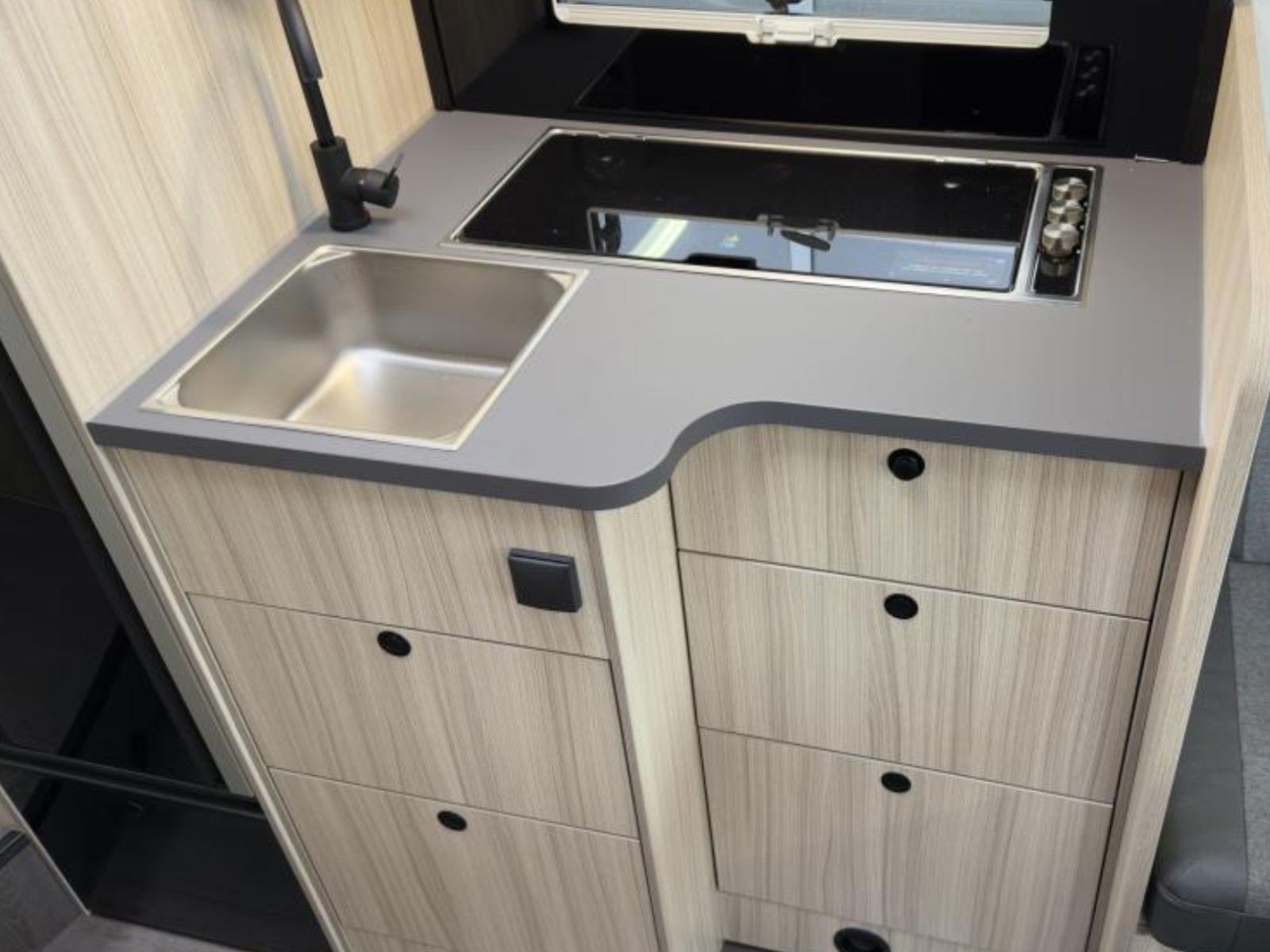 Compacte keuken van de Sun Living S72DL camper, voorzien van een gasfornuis, spoelbak en opbergruimte, uitgevoerd in een modern design